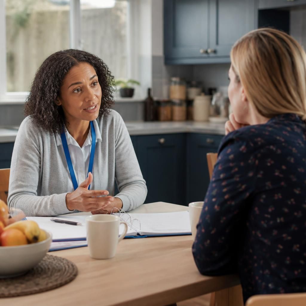 Foster carer speaking with a social worker at a kitchen table